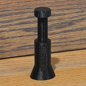 May include: A black adjustable furniture leveler with a threaded shaft and a textured top. The base flares out, and the side has the text "FTX". The leveler is designed to stabilize furniture.