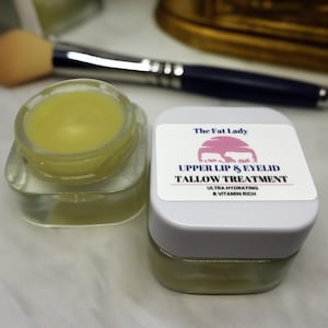 May include: Two small jars of a light yellow balm, one labeled "The Fat Lady Upper Lip & Eyelid Tallow Treatment Ultra Hydrating & Vitamin Rich".