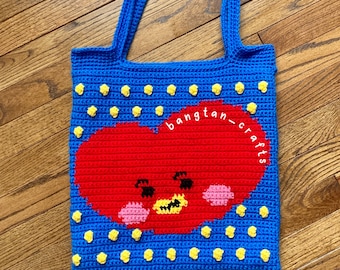 May include: A blue crocheted tote bag with a red heart-shaped character and yellow polka dots. The bag has the text "bangtan_crafts" on the side.