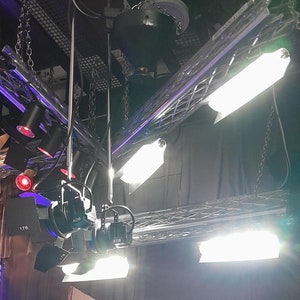 Peut inclure: Mise en scène avec éclairage zénithal et une poupée en veste en cuir noir et jean assise à une table blanche. Des chaises rouges et une boule disco sont également visibles. La poupée porte un t-shirt noir avec du texte blanc.