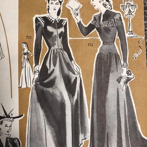 May include: Two women wearing long, black dresses with white trim. The woman on the left is holding a white card. The woman on the right is holding a small, white purse. The image is from a vintage sewing pattern book. The numbers 711 and 712 are visible in the image.