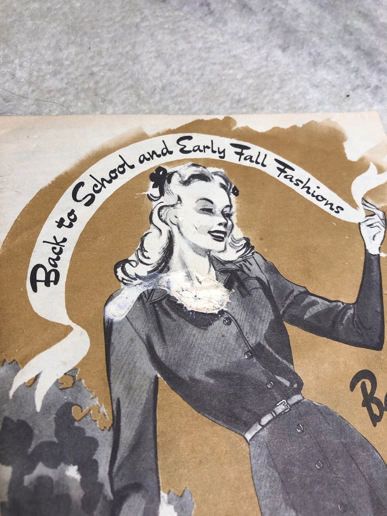 May include: A vintage advertisement for back to school and early fall fashions. The ad features a woman wearing a dark gray dress with a belt and a white blouse. The text "Back to School and Early Fall Fashions" is written in a cursive font on a brown background.