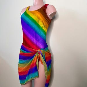 May include: A rainbow swimsuit with a matching rainbow sarong. The swimsuit has a scoop neck and a racerback style. The sarong is tied at the waist.