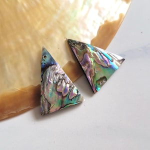 May include: Two iridescent abalone shell triangle pendants. The pendants display a shimmering array of colors, including blues, greens, purples, and hints of gold. The triangular shape is a unique design element.