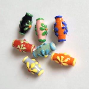 以下が含まれることがあります： 花柄のデザインが施された、カラフルなガラスビーズのコレクション。ビーズは黒、ピンク、オレンジ、青、赤、黄色など様々な色があります。それぞれのビーズには、対照的な色を使ったユニークな花柄が施されています。