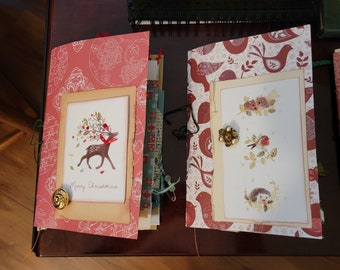 May include: Two handmade journals with red and white patterned covers. The left journal features a deer illustration with the text "Merry Christmas". The right journal features a bird, hedgehog and squirrel illustration.