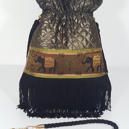 Golden quilted lame handbag. Bronze handbag with shops bangs. Handbag with black bangs. Gold and black shoulder bag.