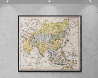 May include: An antique map of Asia with a black frame. The map is printed on paper with a cream background and features a variety of colors, including yellow, green, blue, and brown. The map is titled in Arabic script.