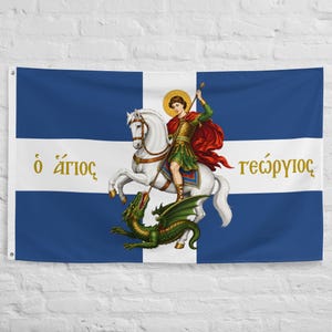 Puede incluir: Una bandera rectangular con fondo azul y una cruz blanca. En el centro hay una ilustración de una figura con armadura sobre un caballo blanco, atravesando a un dragón verde con una lanza. El texto griego "ὁ ἅγιος" y "γεώργιος" está impreso en oro.