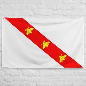 May include: A white flag with a red diagonal stripe and three yellow bee silhouettes. The flag is hanging on a white brick wall.