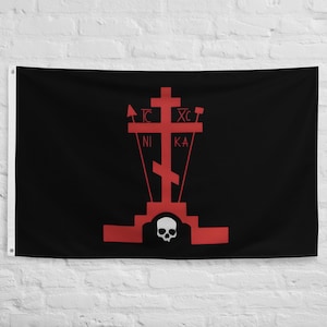 May include: Black flag with a red Orthodox cross design. The cross features the letters TC, XC, NI, and KA, along with a skull at the base. The flag is rectangular and hangs against a white wall.