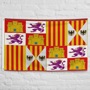 Puede incluir: Bandera rectangular con un patrón repetido de castillos amarillos, leones morados y rayas rojas y amarillas. La bandera también presenta triángulos blancos con águilas negras. La bandera está colgada contra una pared de ladrillos blancos.