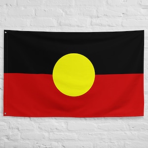 Op de afbeelding: Een zwarte, rode en gele vlag met een grote gele cirkel in het midden. De vlag staat bekend als de Aboriginal Flag van Australië.