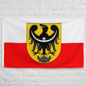 May include: A rectangular flag featuring a horizontal bicolor design of white on the top half and red on the bottom half. Centered on the flag is a yellow shield displaying a black eagle with a white crescent moon and a small cross on its chest.