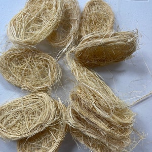 May include: A pile of natural, beige, dried grass or straw, resembling bird nests, for crafting or decorative purposes.