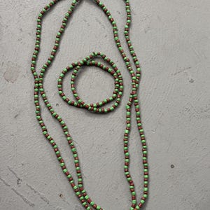 May include: A necklace and bracelet set featuring small, round beads in alternating green and brown colors. The necklace is long and draped, while the bracelet is circular.
