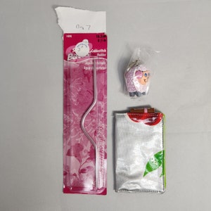 Peut inclure: Un porte-clés en forme de mouton rose et blanc, un enfile-aiguille argenté et une pochette zippée argentée et blanche avec un motif de pomme rouge. La pochette mesure 15,2 cm de long.