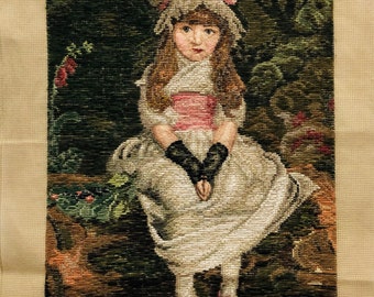 May include: Needlepoint canvas featuring a girl in a white dress and pink hat sitting on a rock with green foliage in the background. The artist's name, "JOHN EVERETT MILLAIS", is printed at the bottom of the canvas.