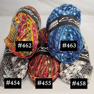 May include: A selection of Erdal Lotus yarn skeins in assorted colours. The skeins are labelled with numbers #462, #463, #454, #455, and #458. The yarn has a textured look with metallic threads, ideal for knitting and crochet.