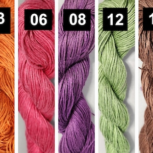 Könnte beinhalten: Fünf Knäuel Garn in verschiedenen Farben: Orange, Rot, Lila, Grün und Braun. Das Garn besteht aus Naturfasern und hat eine rustikale Textur.