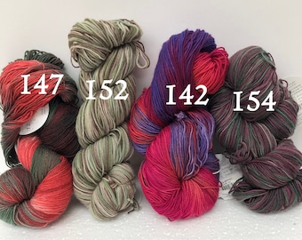Può includere: Quattro gomitoli di filato in diverse combinazioni di colori. I gomitoli sono etichettati con i numeri: 147, 152, 142 e 154.