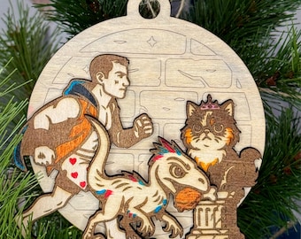 May include: A circular wooden ornament featuring a layered design of a person running in heart-patterned shorts, a small dinosaur holding a round object, and a cat wearing a crown, all set against a background with a faint brick wall pattern.