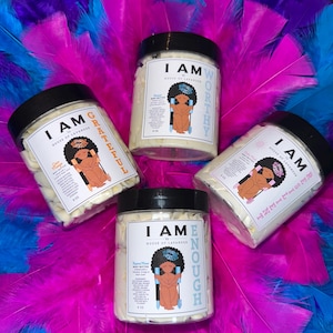 May include: Four jars of body butter with black lids and white labels. Each jar has a different affirmation on the label: "I Am Worthy", "I Am Grateful", "I Am Resilient", and "I Am Enough". Each label features a cartoon illustration of a Black woman sitting on a throne.