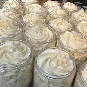 May include: A close-up of multiple jars filled with a thick, white, whipped cream-like substance. The jars are clear glass and the cream is piled high in each jar.