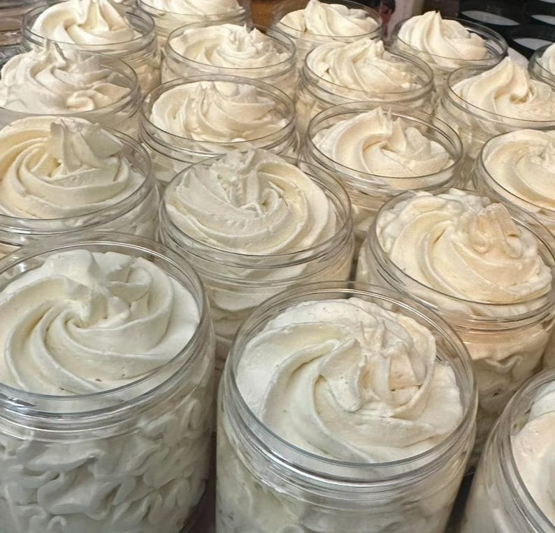 May include: A close-up of multiple jars filled with a thick, white, whipped cream-like substance. The jars are clear glass and the cream is piled high in each jar.