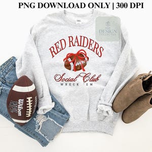 Pode incluir: Um moletom cinza claro com o texto "Red Raiders Social Club Wreck 'Em" em script vermelho. Uma bola de futebol americana marrom com um laço vermelho está centralizada acima do texto. Uma bola de futebol americana marrom e branca e botas marrons também estão na imagem.