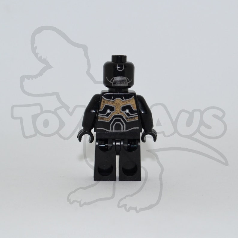 May include: Black Lego minifigure with a gold and black patterned torso and a black helmet with a silver visor.