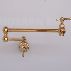 Peut inclure: Un robinet de remplissage de pot mural en or avec un bras pivotant et une poignée à levier. Le robinet a un design traditionnel avec un bec arrondi et un bouton décoratif.