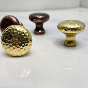 以下が含まれることがあります： 3つのキャビネットノブ。1つはテクスチャ加工されたゴールド仕上げ、1つは滑らかなゴールド仕上げ、1つは銅仕上げです。