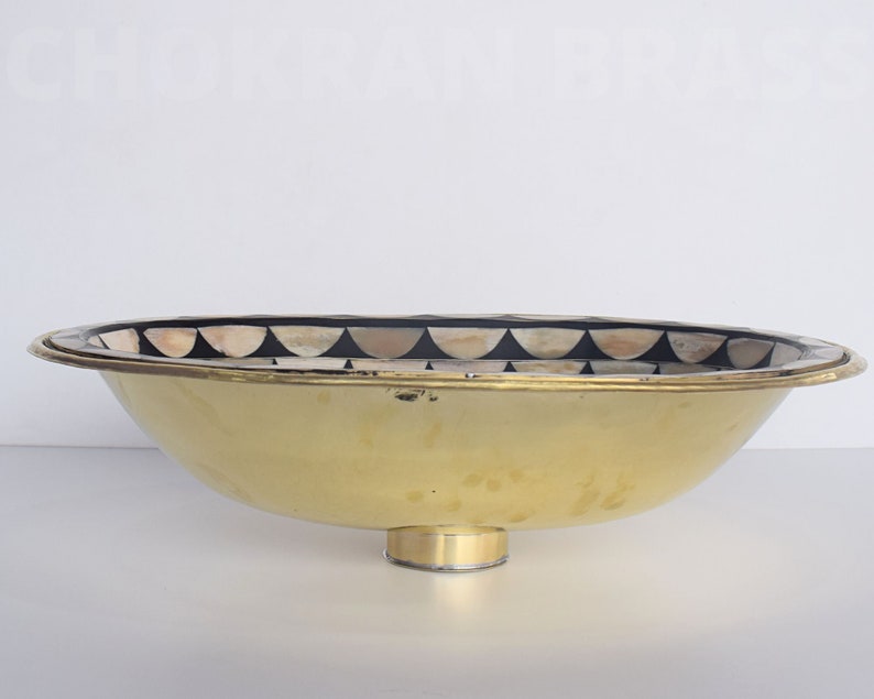Op de afbeelding: Een ovale gouden kom met een decoratieve zwart-witte moza&iuml;ekrand rond de rand. De kom heeft een ronde basis en is gemaakt van metaal.