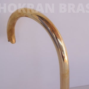 May include: A close-up of a shiny gold-colored metal faucet spout. The spout is curved and has a smooth, polished finish.