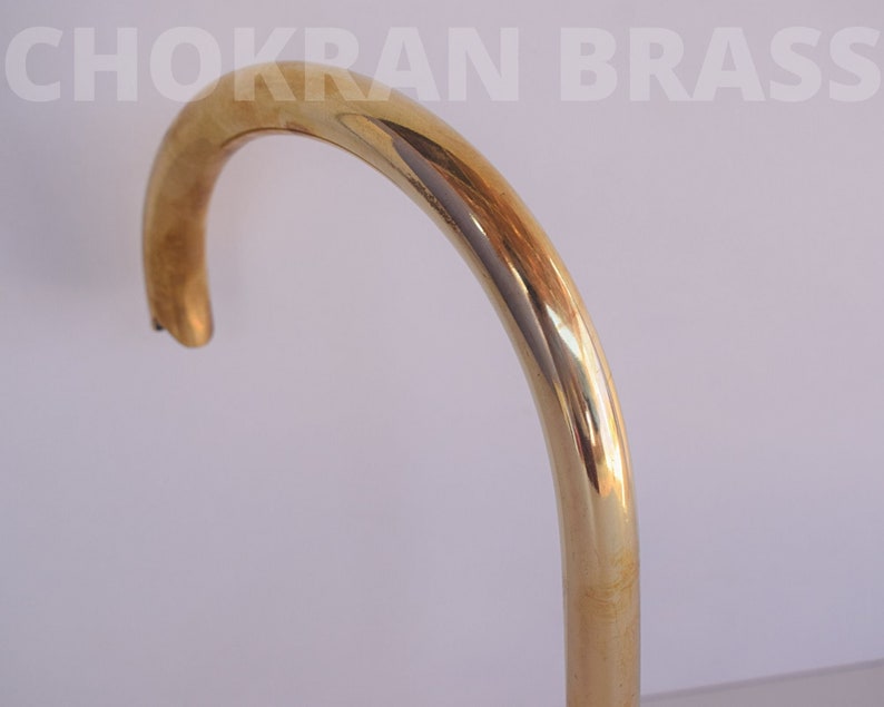 May include: A close-up of a shiny gold-colored metal faucet spout. The spout is curved and has a smooth, polished finish.