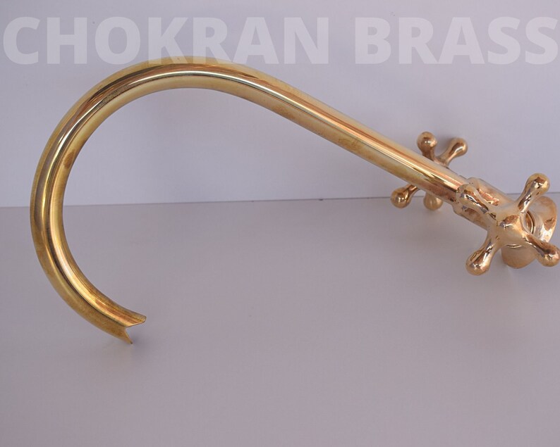 May include: A gold-colored brass faucet with a curved spout and four cross-shaped handles.