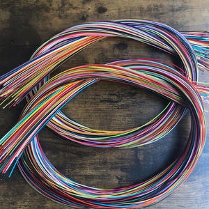 May include: A bundle of colorful wires, arranged in a circular pattern, on a wooden surface.