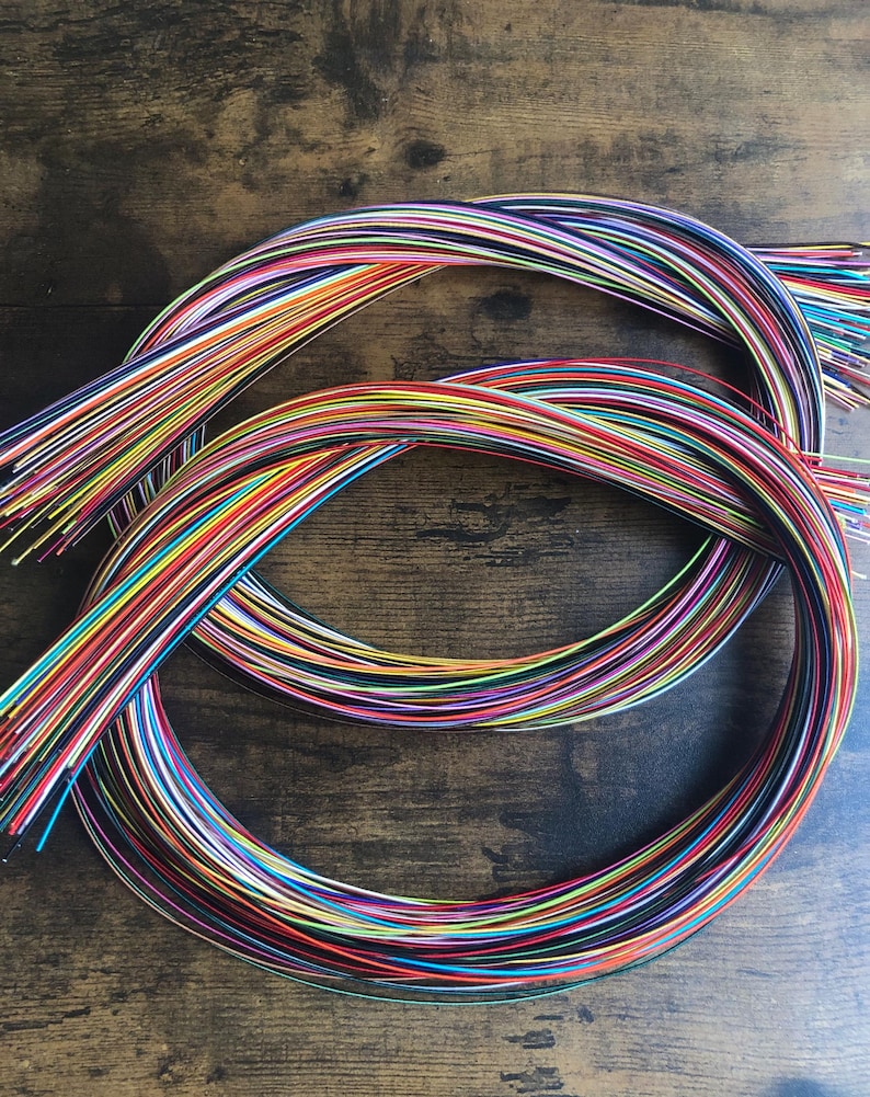 May include: A bundle of colorful wires, arranged in a circular pattern, on a wooden surface.