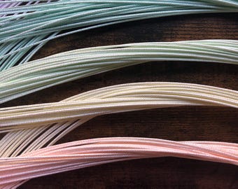 May include: A collection of pastel coloured cords arranged in a rainbow pattern. The cords are made of a soft, silky material and are perfect for crafting or jewellery making.