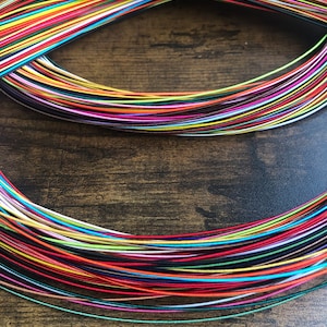 May include: A bundle of colorful embroidery floss spools, arranged in a circular pattern. The floss is a variety of colors, including red, blue, green, yellow, and purple.