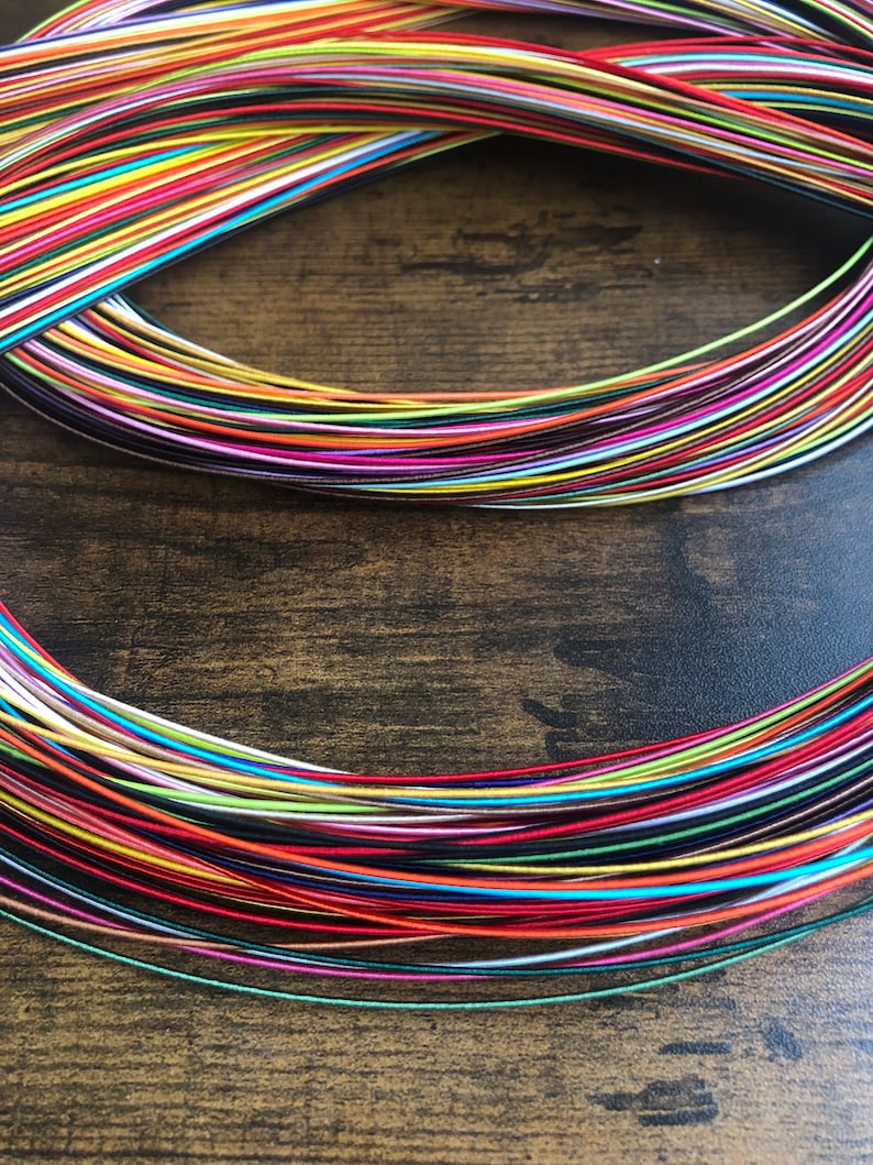 May include: A bundle of colorful embroidery floss spools, arranged in a circular pattern. The floss is a variety of colors, including red, blue, green, yellow, and purple.