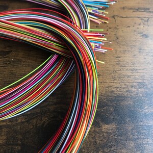 May include: A bundle of colorful embroidery floss spools, arranged in a circular pattern. The floss is a variety of colors, including red, blue, green, yellow, and purple.