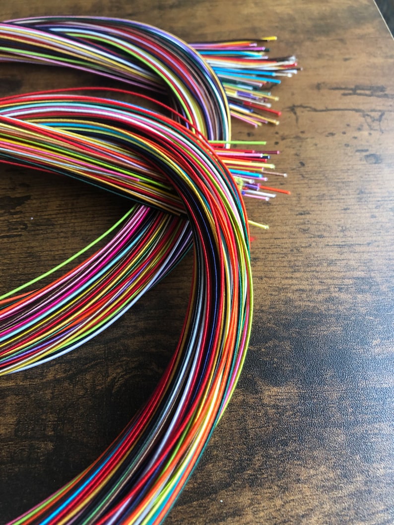May include: A bundle of colorful embroidery floss spools, arranged in a circular pattern. The floss is a variety of colors, including red, blue, green, yellow, and purple.