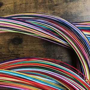 May include: A collection of colorful embroidery floss spools arranged in a rainbow pattern. The floss is wound around itself in a circular shape, creating a visual display of vibrant hues.