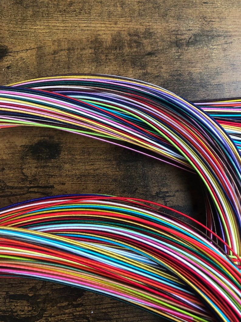 May include: A collection of colorful embroidery floss spools arranged in a rainbow pattern. The floss is wound around itself in a circular shape, creating a visual display of vibrant hues.