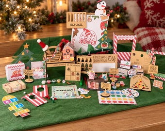 May include: A collection of miniature holiday-themed props and games including an Elf Jail, Elfopoly board, a kissing booth, a hopscotch mat, and various signs with text like North Pole Pizza, Tic-Tac-Hohoho, and Movie Night on a green surface.
