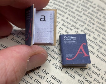 May include: Two miniature books, one open to the letter "a" and the other closed with the title "Collins English Dictionary & Thesaurus" and the letter "A" on the cover.