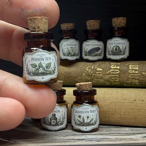 May include: Small apothecary bottles with cork stoppers. Each amber glass bottle features a white label with botanical illustrations and text, including "Poison Ivy" and "Dandelion Root". The bottles are arranged on a stack of old books.