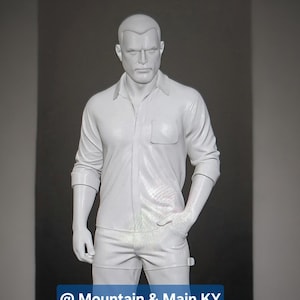 May include: A solid white, full-body mannequin of a person with short hair, wearing a button-down shirt with a chest pocket and long pants. The figure stands in a neutral pose with one hand in a pocket. A blue rectangular label displays @ Mountain & Main KY.